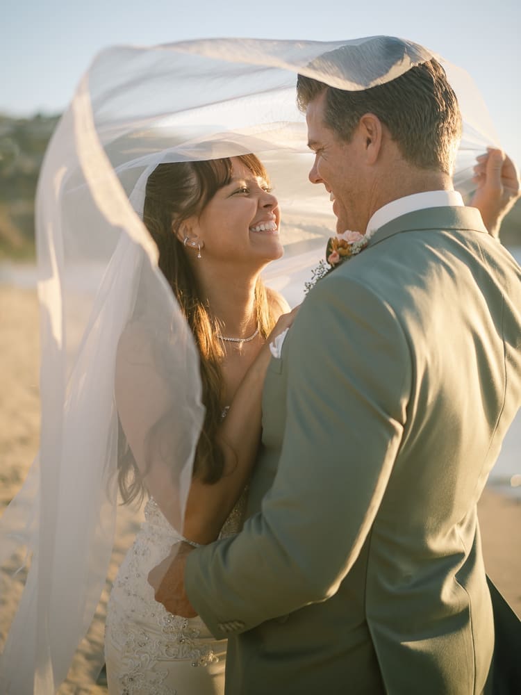 Bride and groom under veil on Torrance Beach