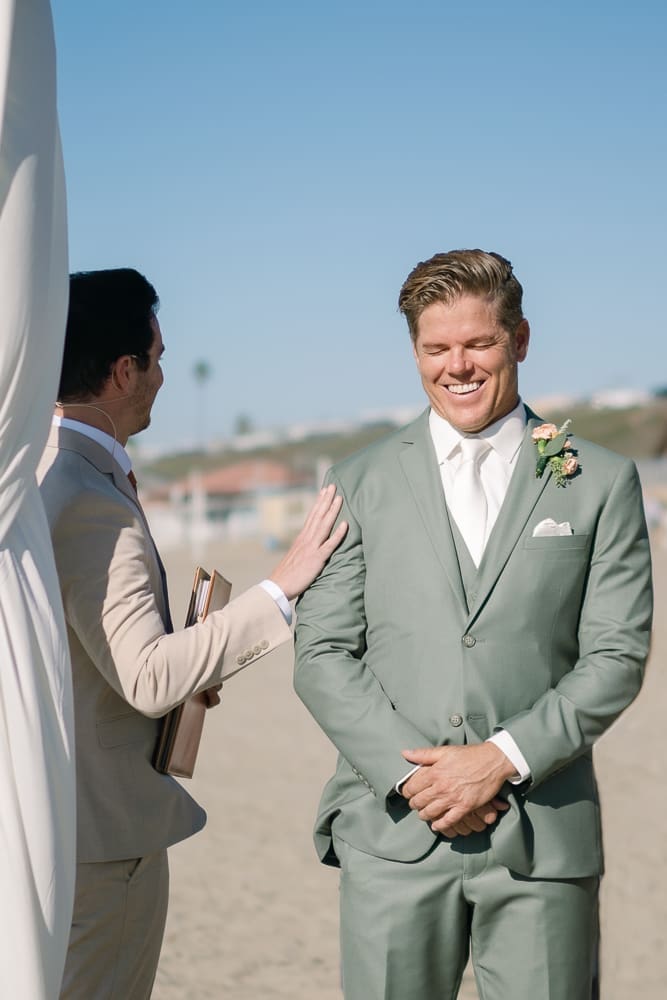 Groom and officiant waiting at arch of wedding ceremony on Torrance Beach