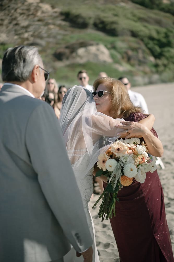 Mother kissing bride at Torrance Beach wedding ceremony